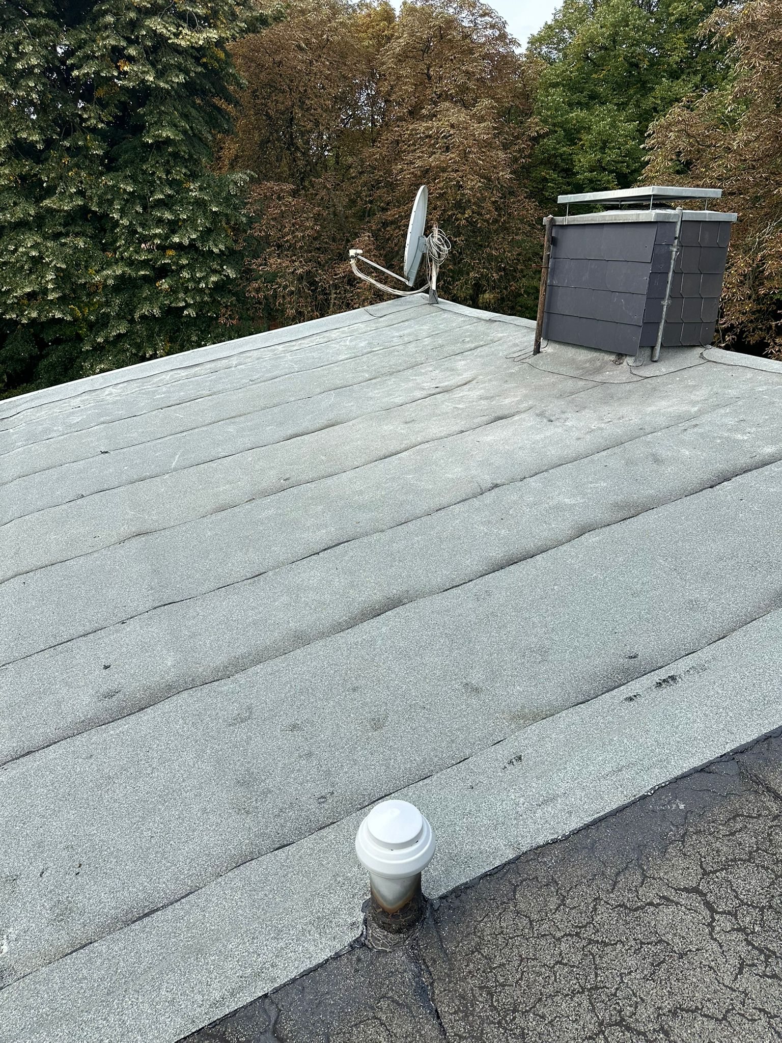 Gealterte Flachdachabdichtung mit sichtbaren Nähten und Durchdringungen