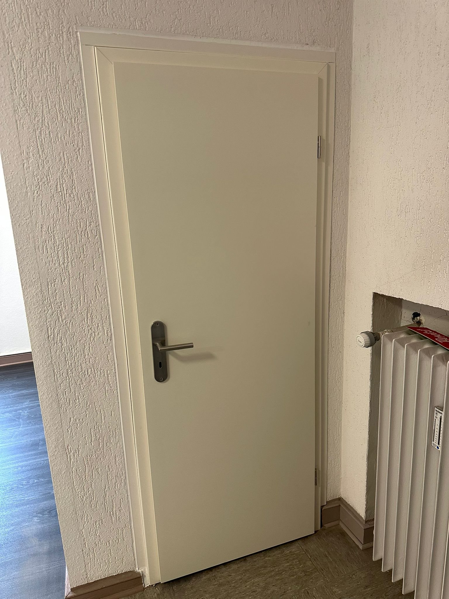 Neue Tür mit Türzarge und Schloss in einem renovierten Bestandsflur
