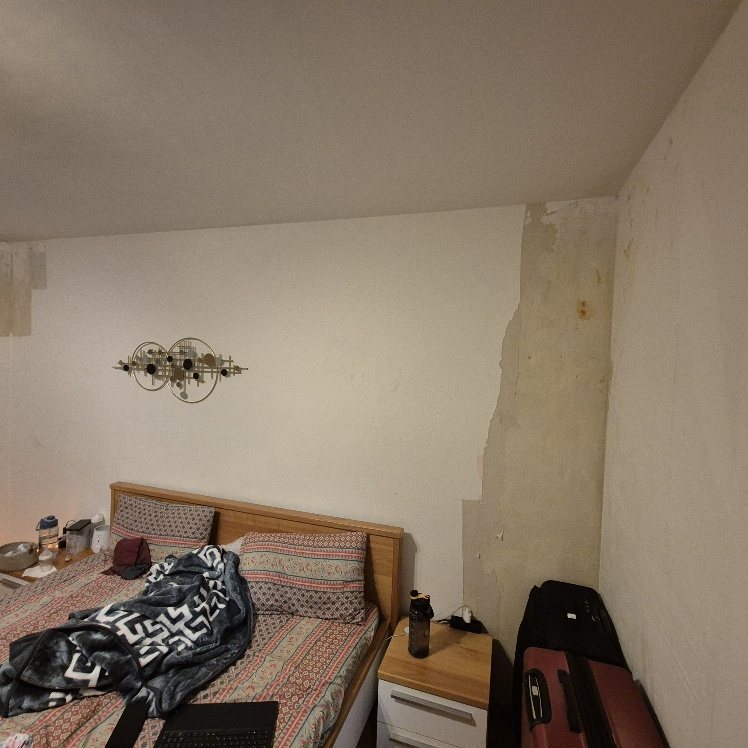 Seitliche Ansicht des Schlafzimmers mit beschädigtem Putz nach Wasserschaden