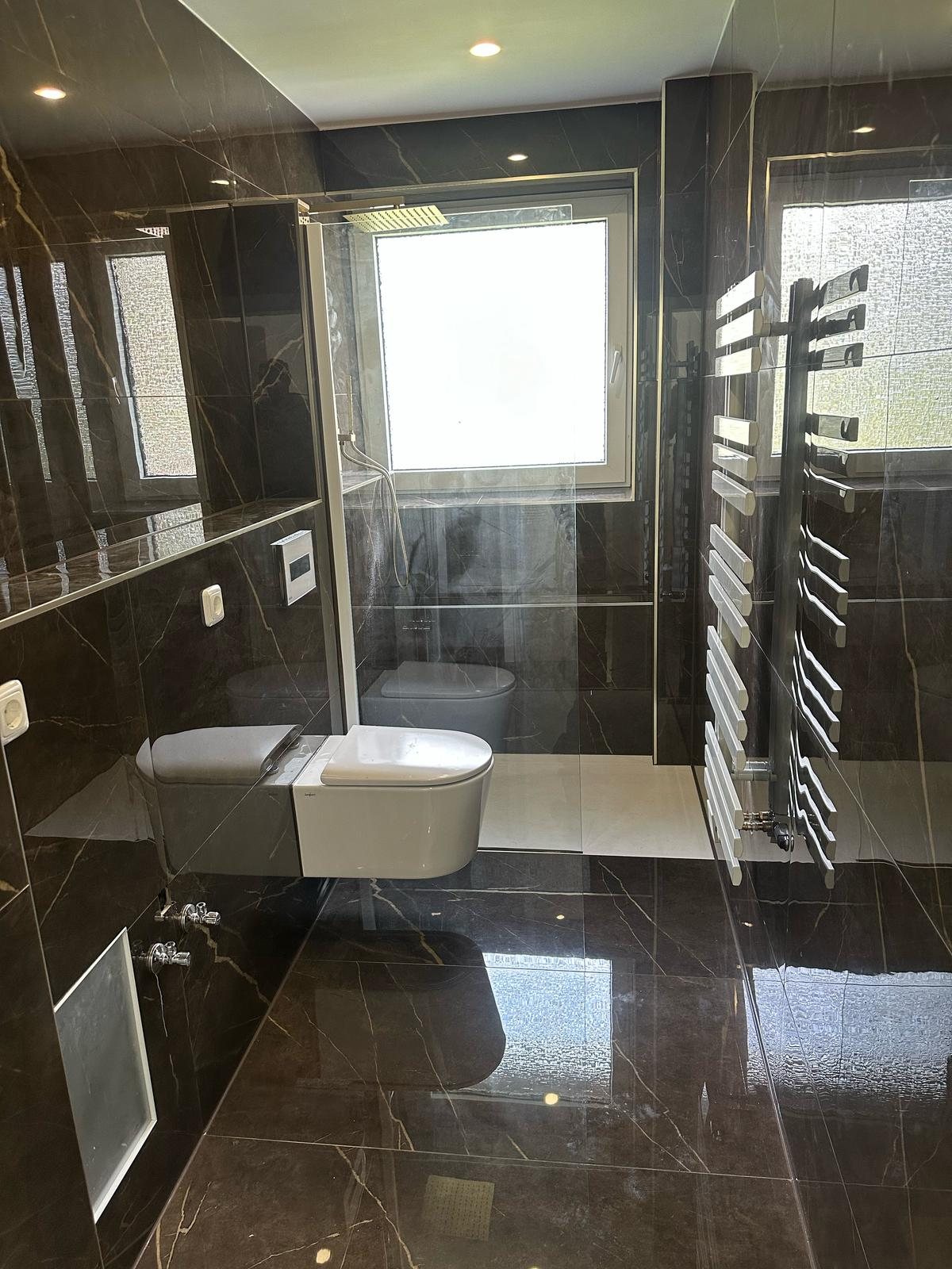 Modern saniertes Badezimmer mit wandhängendem WC und glänzenden Fliesen in Oberhausen